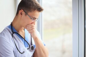 Young doctor thinking while looking out a window