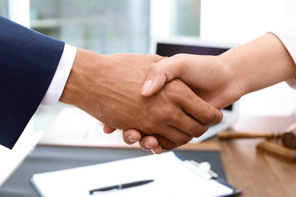 male lawyer shaking hands with female client after winning medical malpractice case