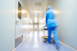 doctor in scrubs pushing cart down hospital hallway