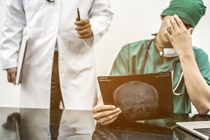 An Introduction to Medical Malpractice - doctor with head in hand looking at x-ray
